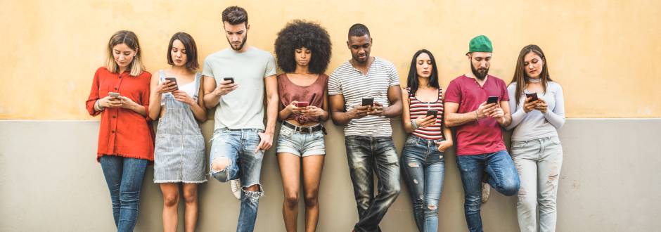 groupe de personnes regardant leurs smartphones dans la rue