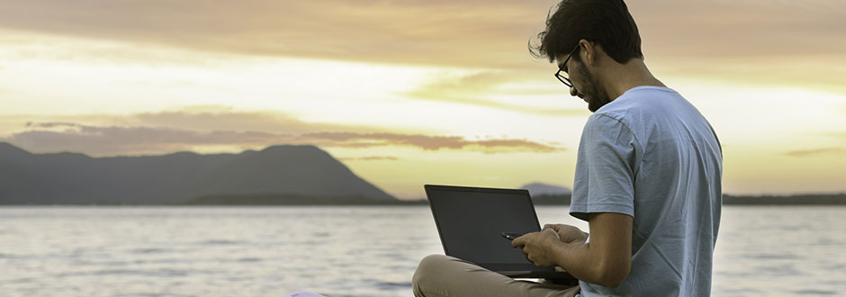 Digital nomade travaillant face à la mer tout en cherchant une solution pour recevoir son courrier