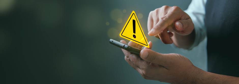 personne avec un smartphone en main, avec le symbole du danger