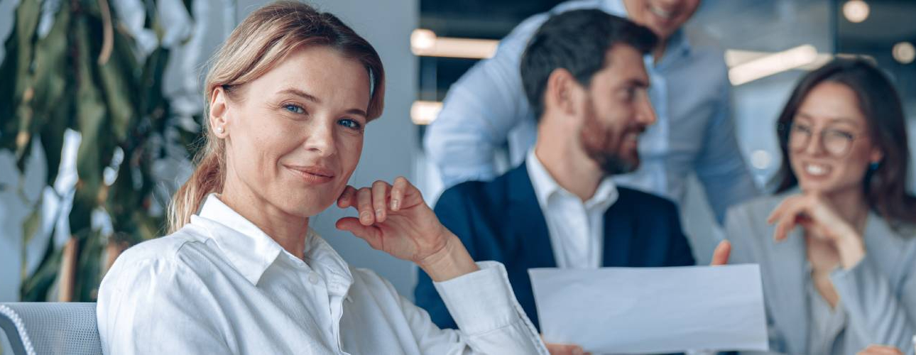 1 dirigeante d'entreprise regarde de face . 3 autres salariés en arrière plan 