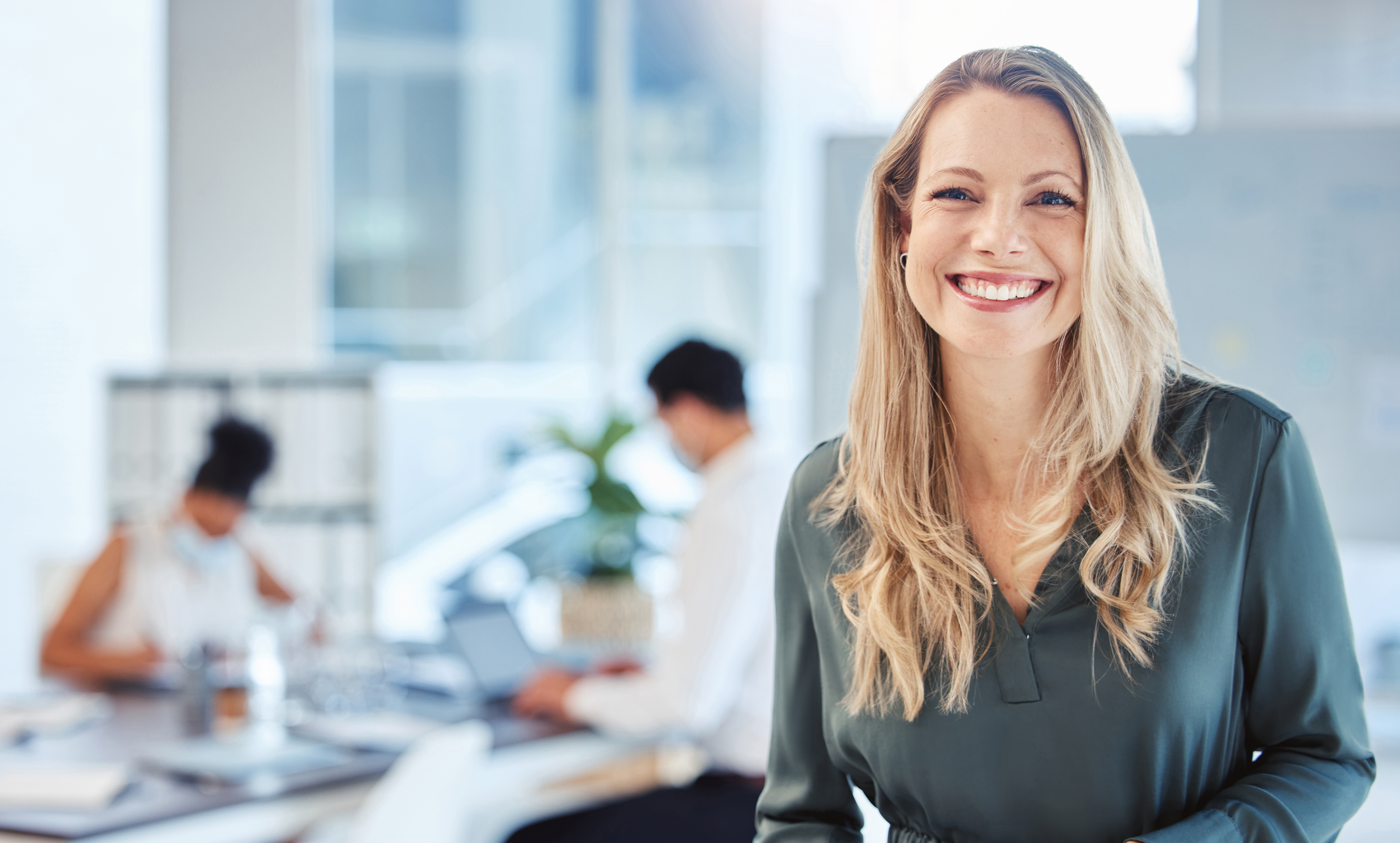 Femme souriante dans un bureau avec équipe derrière au travail fond flous