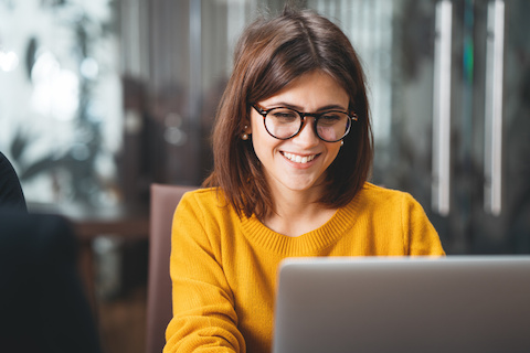 Visuel d'illustration jeune femme brune pull jaune regardant ordinateur en souriant API Lettre recommandée La Poste