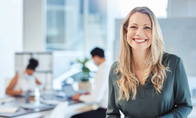 Femme souriante dans un bureau avec équipe derrière au travail fond flous