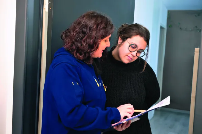 Photo d'illustration remise commentée d'un document par une factrice La Poste à une dame